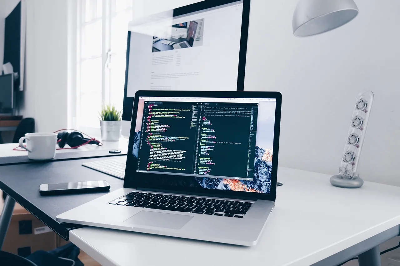 Notebook aberto com código na tela, sobre a mesa de trabalho